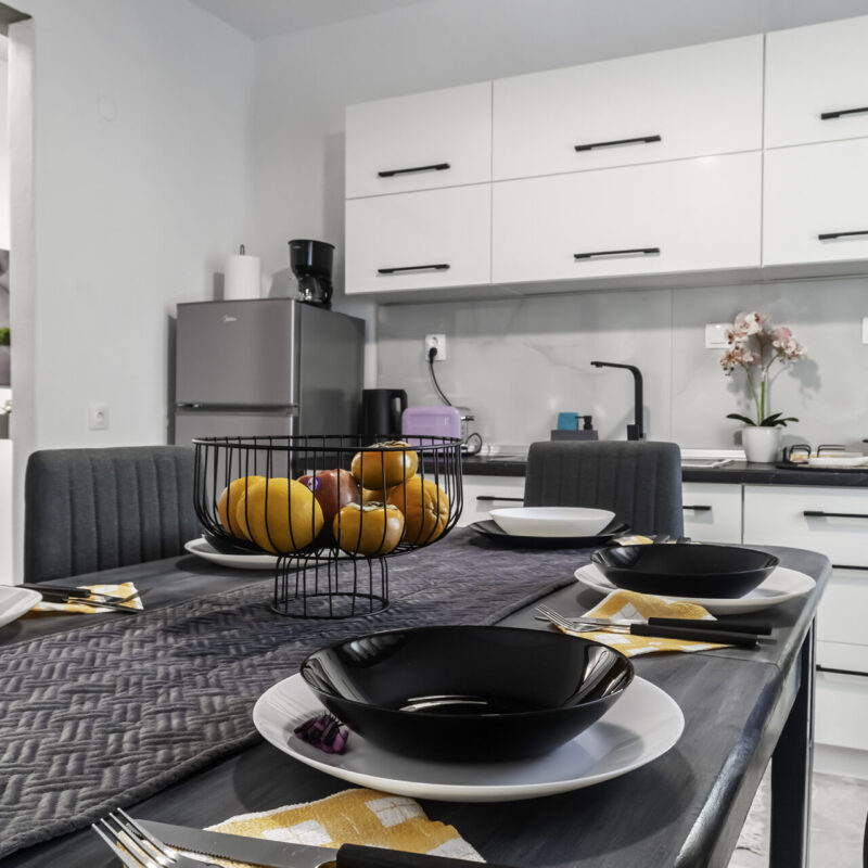 Elegant Dining Setup at Margio Bay Black Plates, Decorative Fruit Bowl, and Modern Appliances