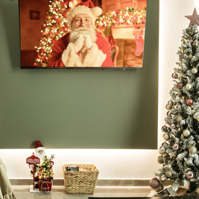 Festive Living Room at Margio Bay Cozy Christmas Tree and Cheerful Santa on TV